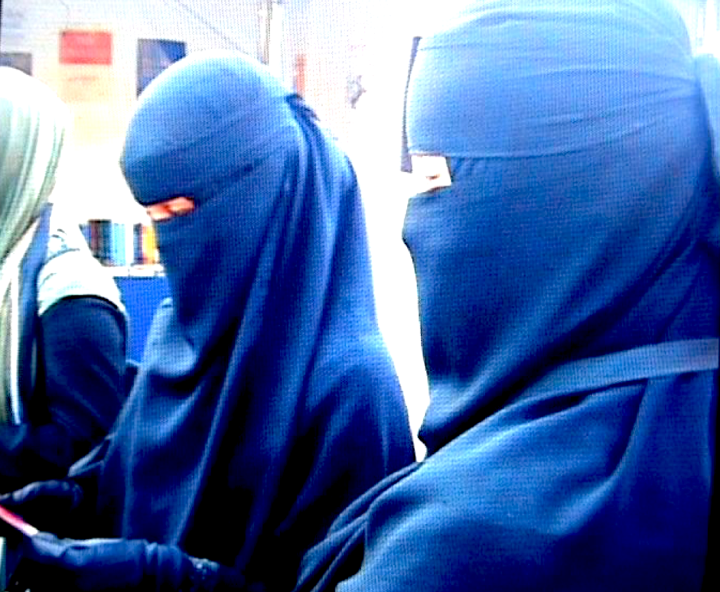 Muslim women in full blue hijab reading UNBOWED promo card